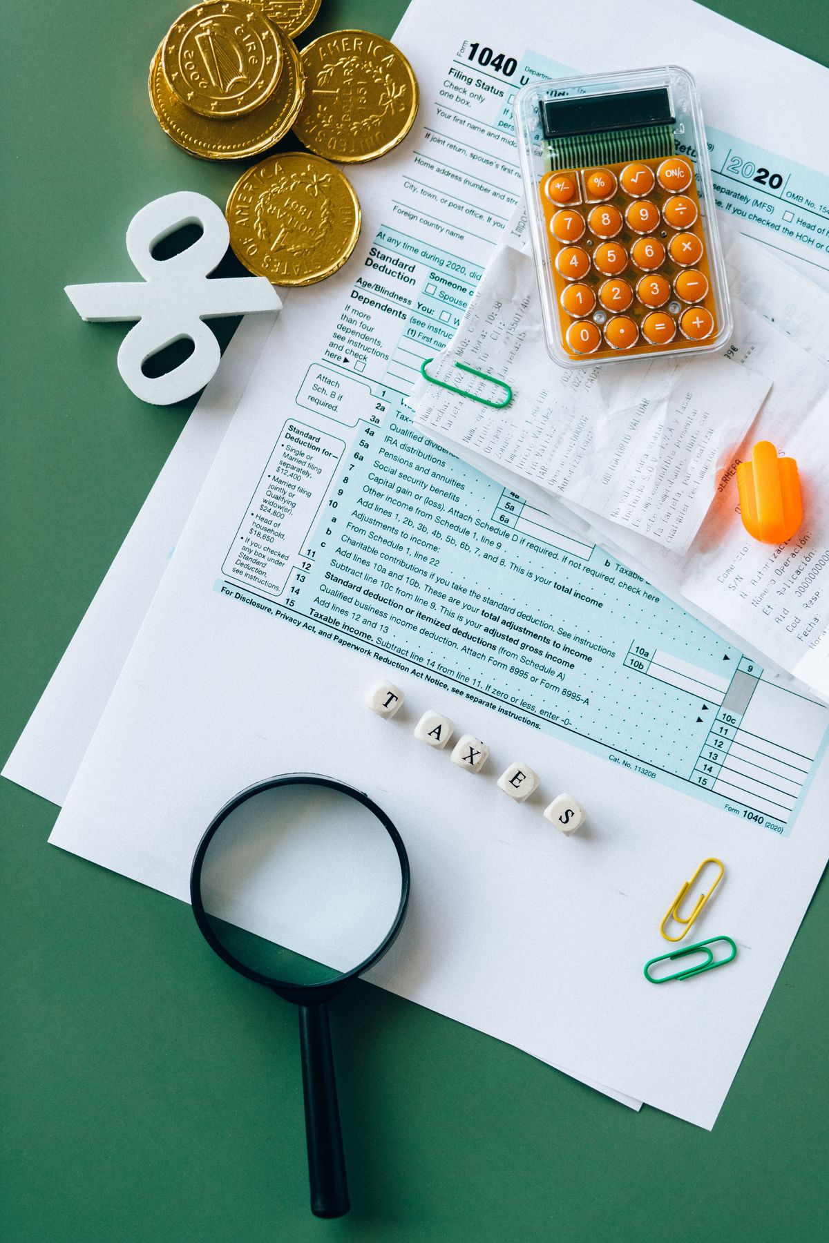 Top view of tax forms, calculator, coins, and office supplies on a desk for tax preparation