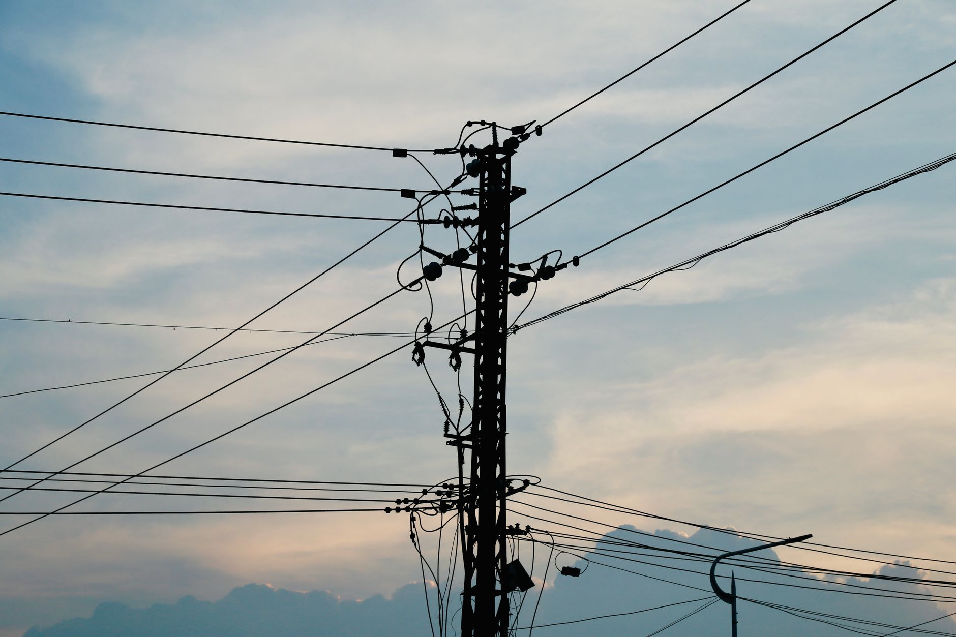 Silhouette of power lines and pole against a vibrant sunset