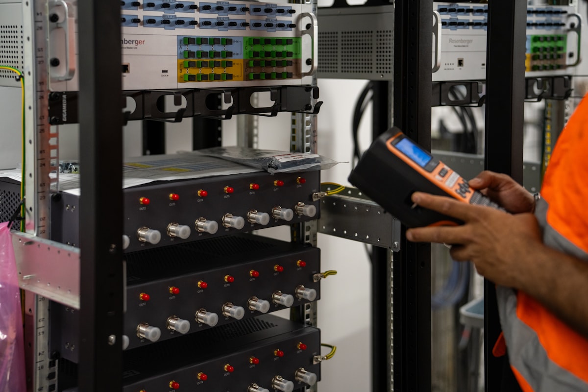 Technician inspecting server racks with a handheld diagnostic tool in a data center facility