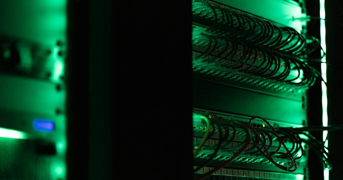 Equipment racks and patch panels lit at night in a darkened facility