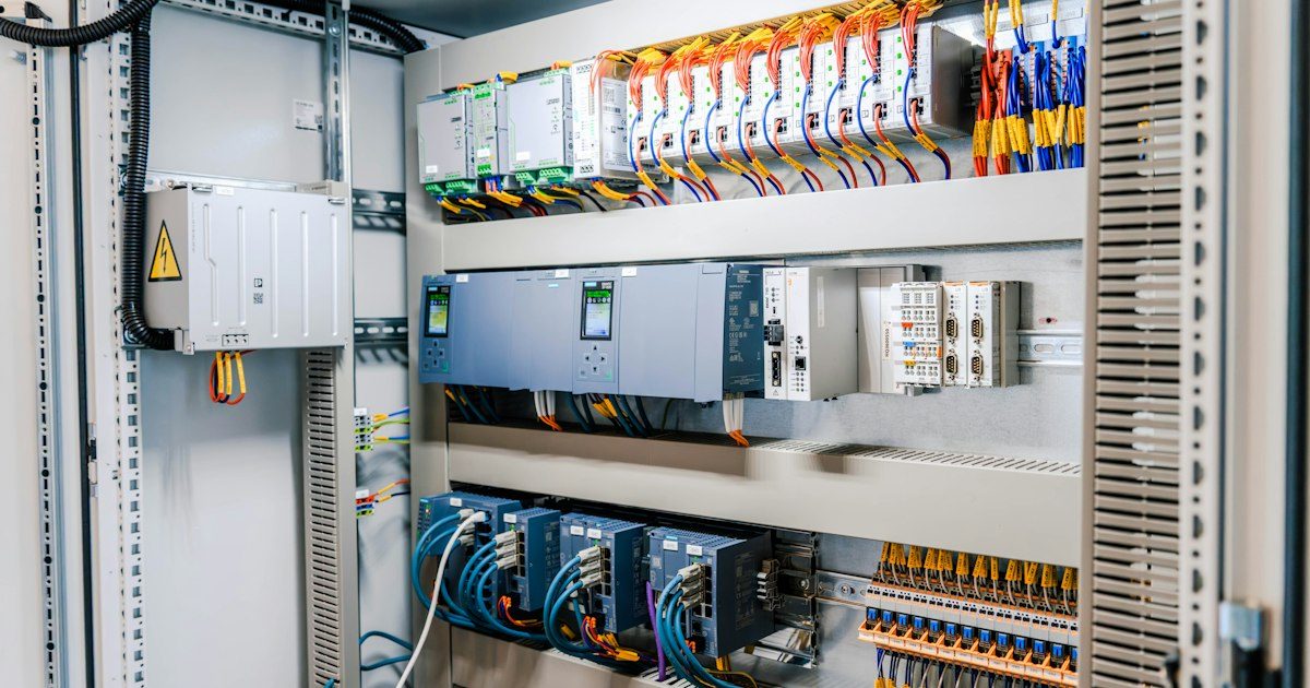 Open industrial electrical control panel showing circuit breakers, relays and terminal wiring