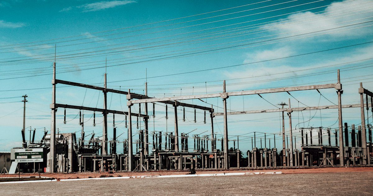 Outdoor electrical substation with transformers, bus structures and overhead lines under a blue sky